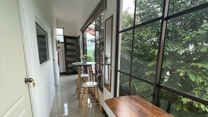 A corridor with a wooden table and chairs, large windows, and a door. - Escape a la Ciudad en Nuestro Encantador Apartamento con Todas las Comodidades (San Rafael Arriba de Desamparados)