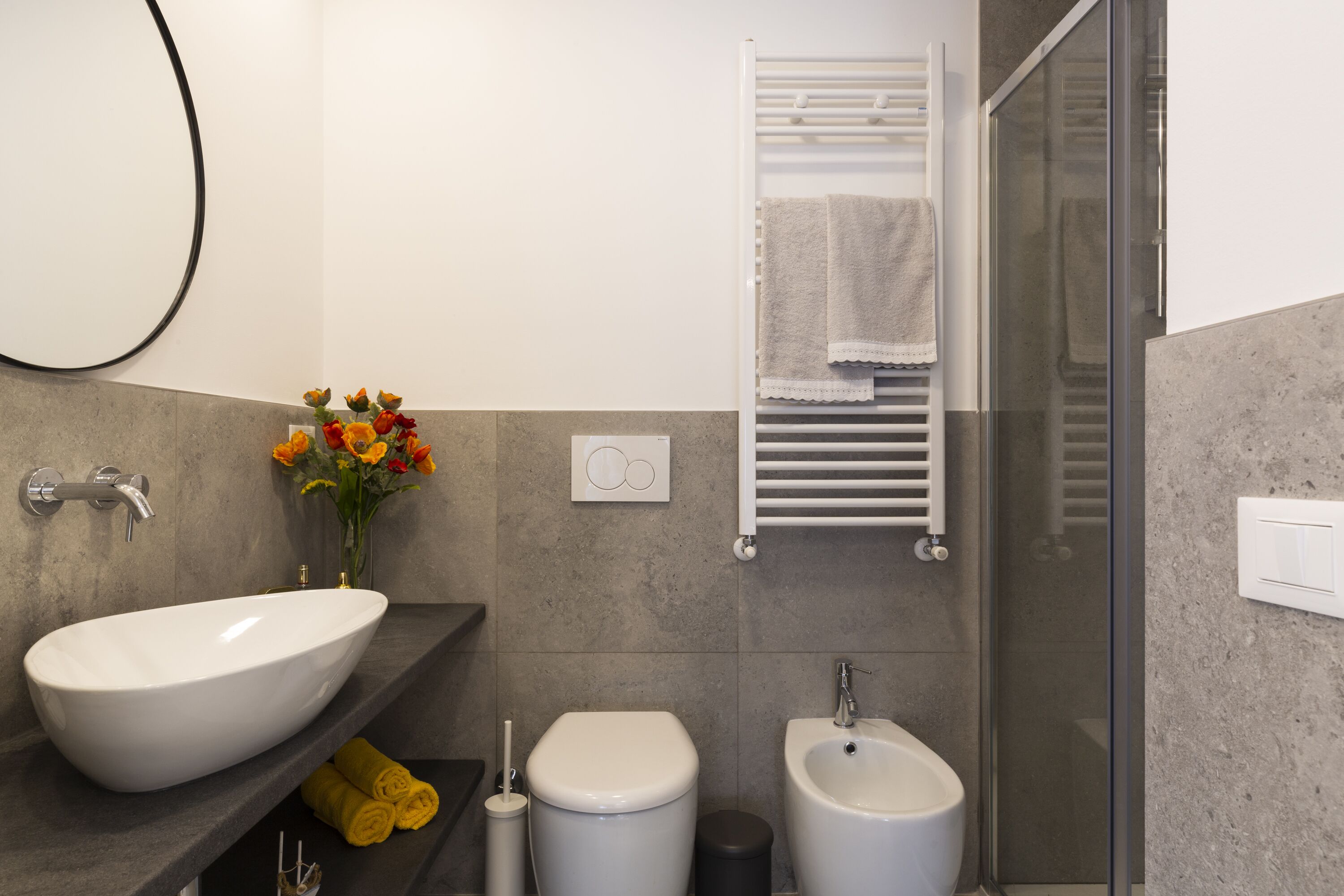 Ein modernes Badezimmer mit einem großen, ovalen Waschbecken, Toilette, Bidet und einer Duschkabine.