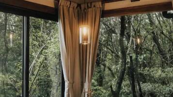 Un baño moderno con una bañera independiente, ventanas amplias y vistas al bosque.