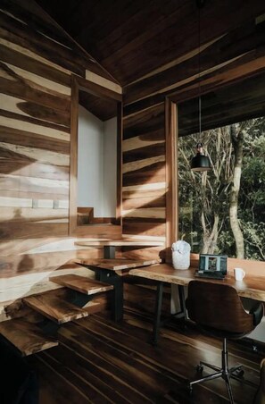 A wooden interior with a desk, chair, and a hanging pendant light.
