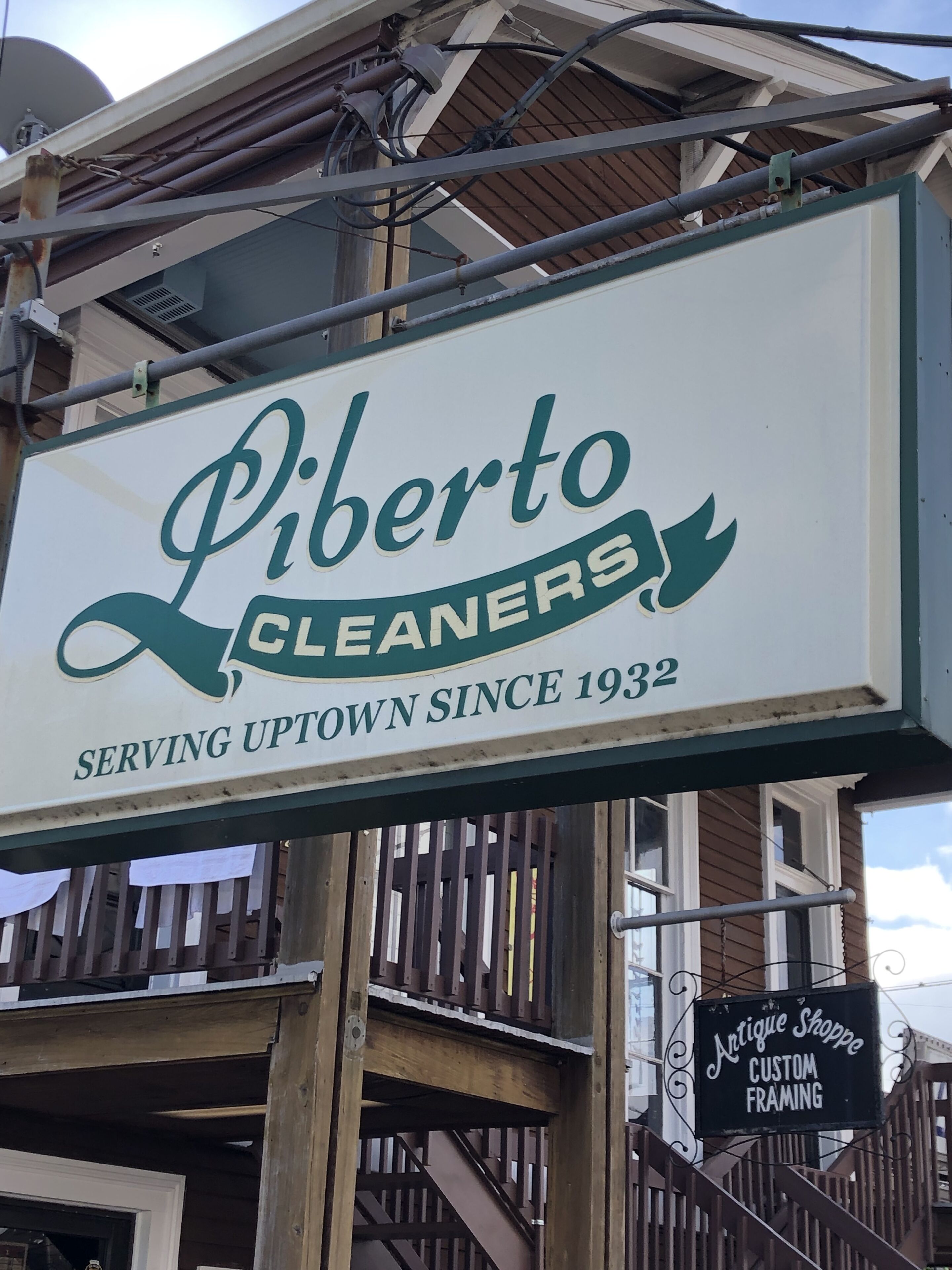 A sign for 'Liberto Cleaners' with a tagline 'Serving Uptown Since 1932'.