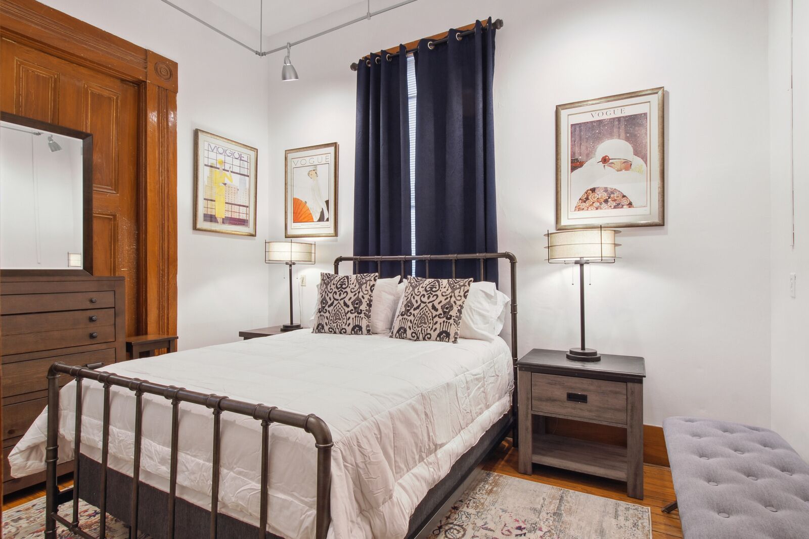 A bedroom with a bed, bedside tables, a dresser, and a window with curtains.