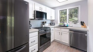 A modern kitchen with stainless steel appliances, white cabinetry, and a window providing natural light.