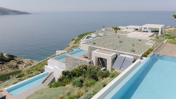 A modern resort with a pool, outdoor seating, and a view of the sea. - Luxury Seafront Villa Eros with Private Pool - Rock Bay Villas - Crete, Greece (Agia Pelagia)