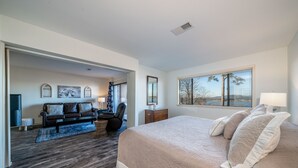 Un dormitorio moderno con una cama grande, un sofá y vistas al exterior a través de una ventana.