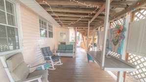 A covered porch with wooden flooring, white railings, and a bench. - Historic 1940's Beach Cottage, steps to the beach!   (Tybee Island)