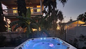 A hot tub with a built-in heater, surrounded by a wooden deck and palm trees. - Historic 1940's Beach Cottage, steps to the beach!   (Tybee Island)