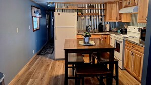 A compact kitchen with wooden cabinets, a white refrigerator, a stove, and a sink. - Cozy Adirondack Retreat sleeps 5, 3 miles to Gore skiing, hiking, rafting (North Creek)