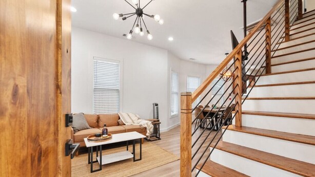 A modern living room with a wooden staircase, a sofa, a coffee table, and a dining area.