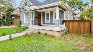 A single-story house with a front porch, a wooden fence, and a well-maintained lawn.