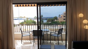 A balcony with a table and chairs, a view of the sea, and a FREUD OLSEN Express sign in the background.