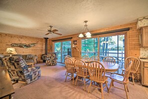 Cozy cabin interior with a comfortable seating area, dining table, and large windows offering views of the surrounding landscape.