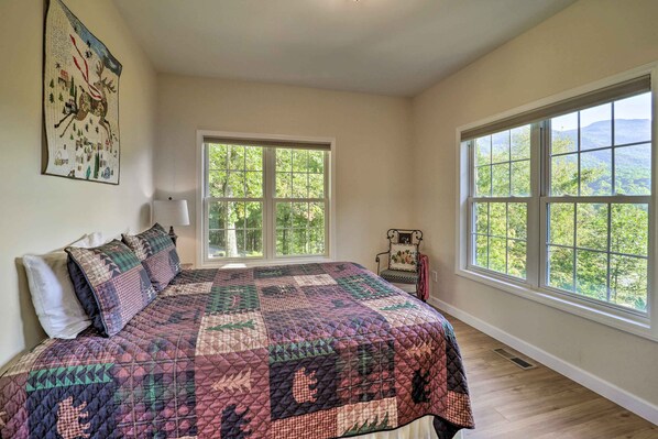 A bedroom with a large bed, two windows, a chair, and a wall hanging. - Near Sugar Mtn Resort! Mtn-View Outdoor Basecamp (Banner Elk)
