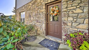 Une maison en pierre avec une porte marron, une fenêtre et un paillasson.