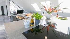 A modern kitchen with a large island, a dining area, and a view of the outdoors. - Gwel y Wyddfa - sleeps 6 guests in 3 bedrooms (Rhosneigr)