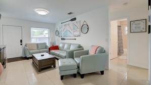A living room with a light blue sofa set, a wooden coffee table, and a framed nautical artwork on the wall. - Steps to the water! 🏝️  (West Palm Beach)