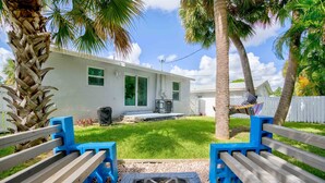 A backyard with a fire pit, a white house, and a hammock. - Steps to the water! 🏝️  (West Palm Beach)