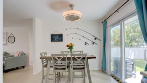 A dining area with a table and chairs, a ceiling fan, and a view through a sliding glass door. - Steps to the water! 🏝️  (West Palm Beach)