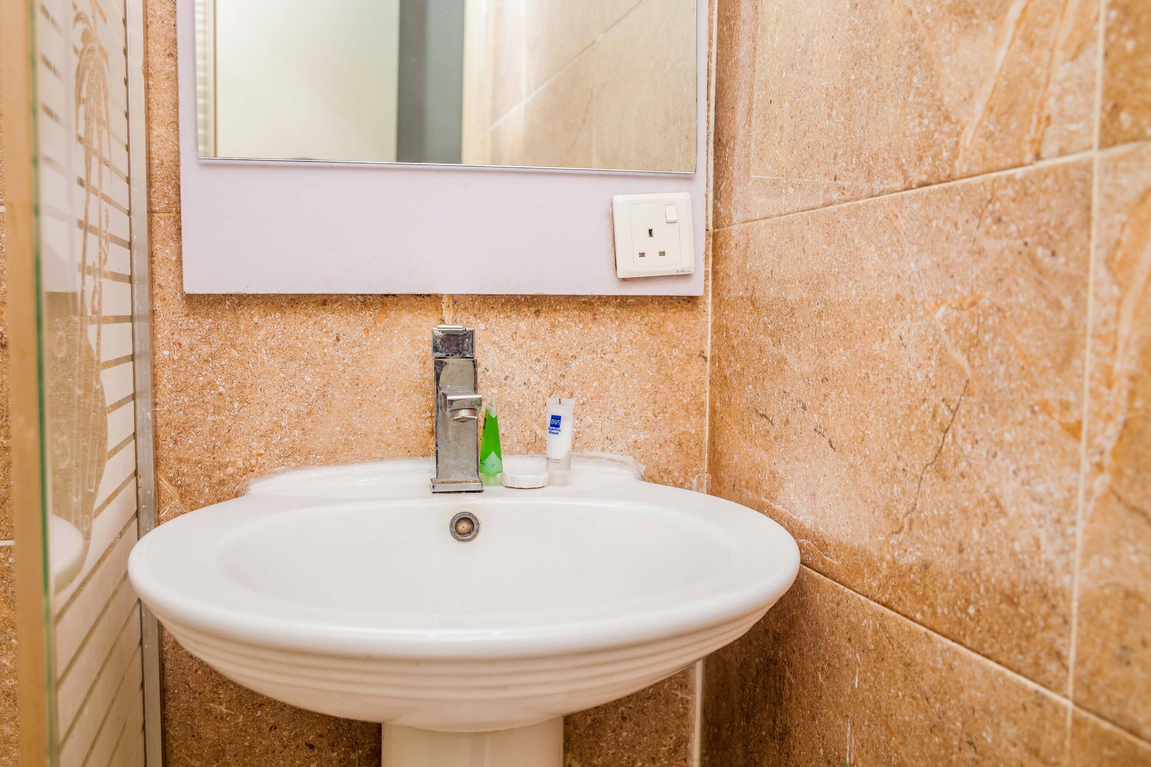 A bathroom with a white sink, a mirror, and toiletries.