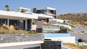Ein modernes mehrgeschossiges Haus mit Naturstein-Fassade, großen Fenstern und einem Pool.