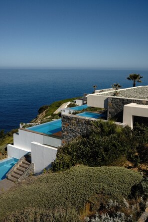 A modern villa with a pool, stone walls, and a view of the sea. - Rock Bay Villas - villa AROMA with 5 Bedrooms and Private Pool (Agia Pelagia)