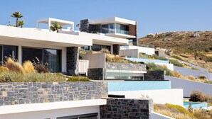 A modern multi-story building with a stone facade, large windows, and a pool area.