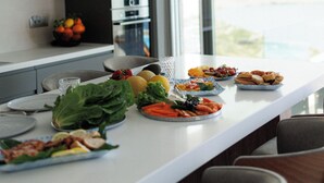 A modern kitchen with a long island, various dishes, and a view through the window.