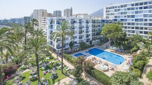 Un hotel con diversi piani, una piscina e palme.