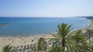 Una spiaggia con palme, ombrelloni e persone.