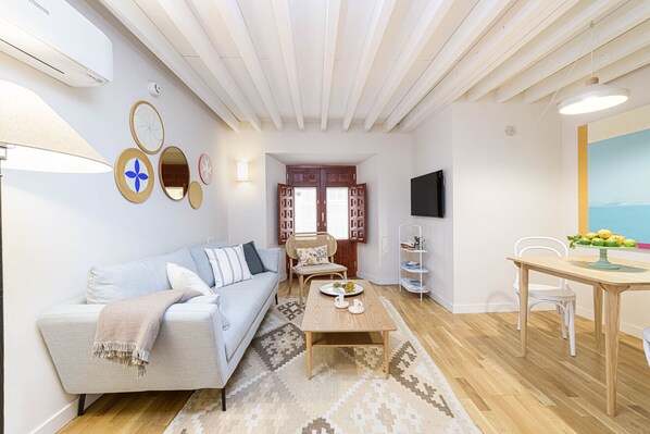 A living room with a sofa, coffee table, and a dining area with a table and chairs.