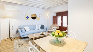 Una sala de estar con un sofá azul, una mesa de centro de madera y un frutero.