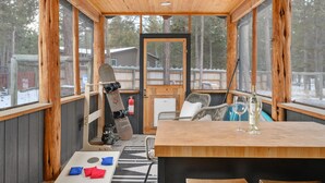 A wooden-paneled room with a table, chairs, a guitar, and a bottle of wine. - Bend Modern Cabin w/ Private Hot Tub . Fenced Yard, Game Room, Pet-Friendly (Bend)