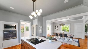 Una cocina moderna con una isla central, hornos empotrados y una zona de comedor con mesa y sillas.
