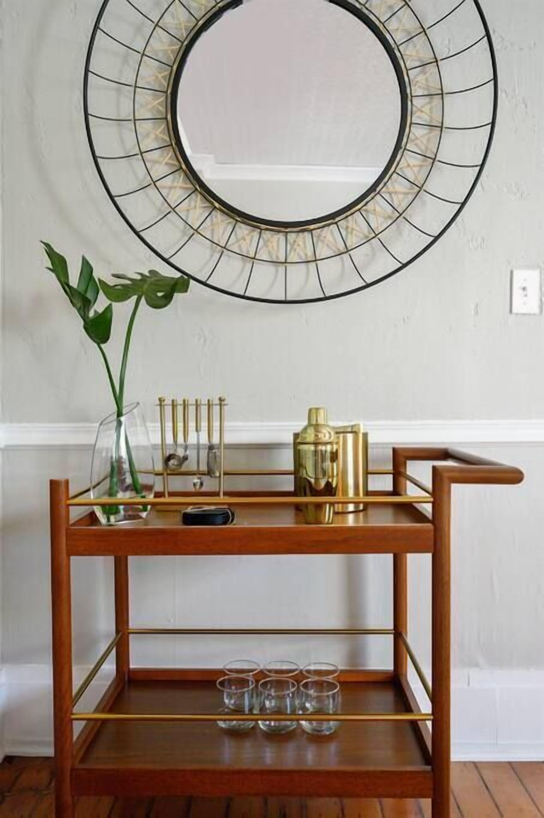 A wooden console table with a glass vase, brass candlesticks, and a brass container.