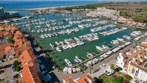 A marina with numerous boats docked, surrounded by residential buildings with red-tiled roofs. - Amazing Apt. in the Heart of Vilm by Centralgarve (Quarteira)