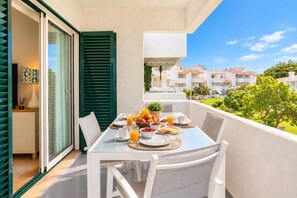 A balcony with a breakfast setup including plates, glasses, and a basket of pastries. - Amazing Apt. in the Heart of Vilm by Centralgarve (Quarteira)