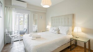 A hotel room with a bed, two bedside tables, a glass table, a chair, a mirror, and an air conditioning unit. - Amazing Apt. in the Heart of Vilm by Centralgarve (Quarteira)