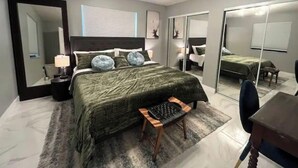 A modern bedroom with a large bed, a desk, a chair, a mirror, and a wardrobe. - Modern Key West look, Pool, Lake, Sleeps 10 (Punta Gorda)