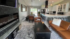 A modern kitchen with a central island, bar stools, and a dining area with a table and chairs. - Modern Key West look, Pool, Lake, Sleeps 10 (Punta Gorda)
