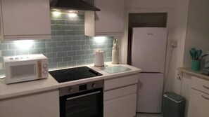 Eine kleine Küche mit Mikrowelle, Herd, Backofen und Kühlschrank.