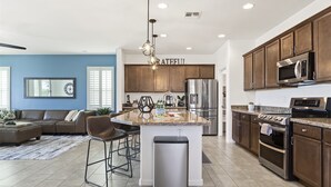 A modern kitchen with a central island, stainless steel appliances, and dark wooden cabinets. - Great Neighborhood, Heated Pool &Spa, Putting Area! (Peoria)