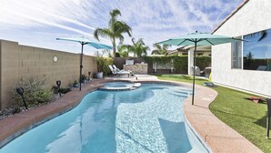 A backyard with a swimming pool, lounge chairs, and umbrellas. - Great Neighborhood, Heated Pool &Spa, Putting Area! (Peoria)