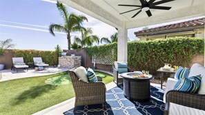 Eine überdachte Terrasse mit Korbmöbeln, einem Grill und einem kleinen Pool.