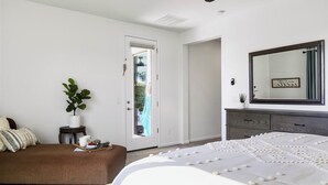 A bedroom with a bed, a dresser, a mirror, a door, and a potted plant. - Great Neighborhood, Heated Pool &Spa, Putting Area! (Peoria)