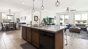 A spacious kitchen with a large island, pendant lights, and a dining area with a table and chairs. - Great Neighborhood, Heated Pool &Spa, Putting Area! (Peoria)