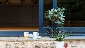 A stone staircase leading to a glass door with a potted plant and a coffee cup on the steps.