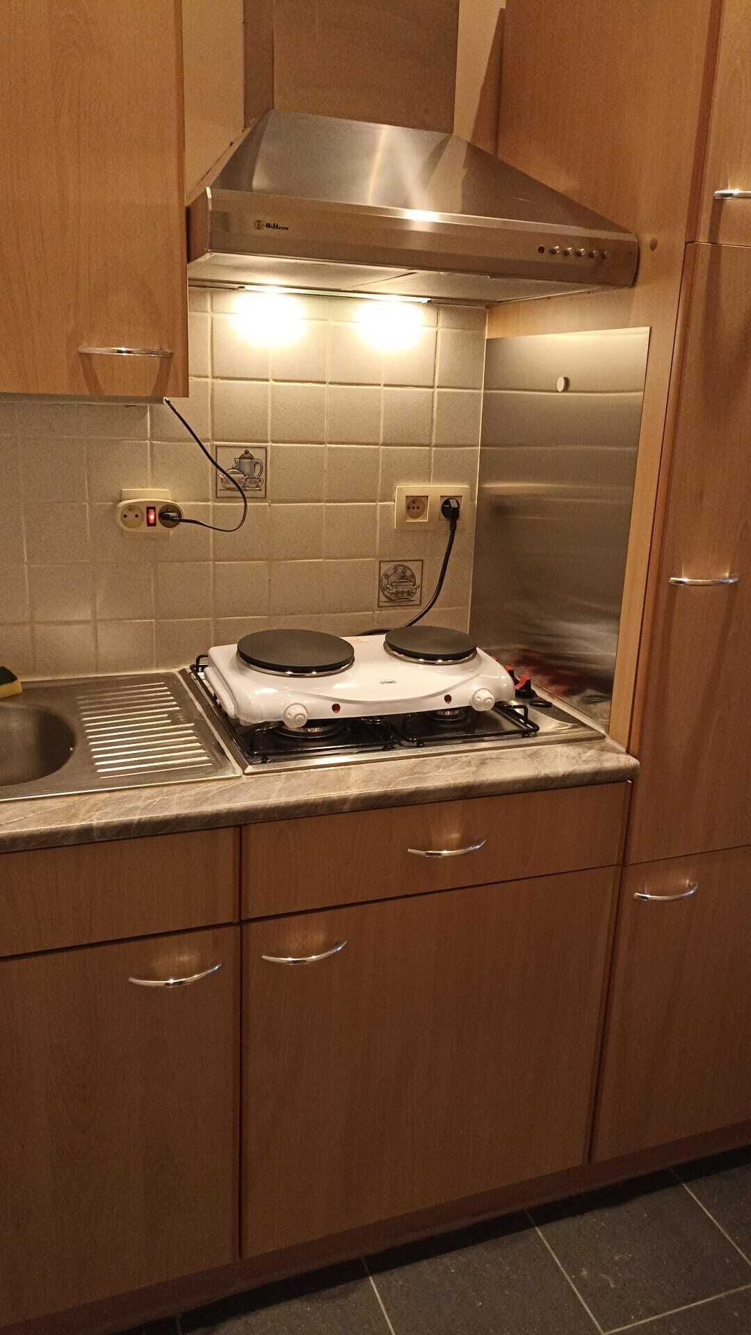 A kitchen with wooden cabinets, a stainless steel range hood, a gas stove, and a sink.