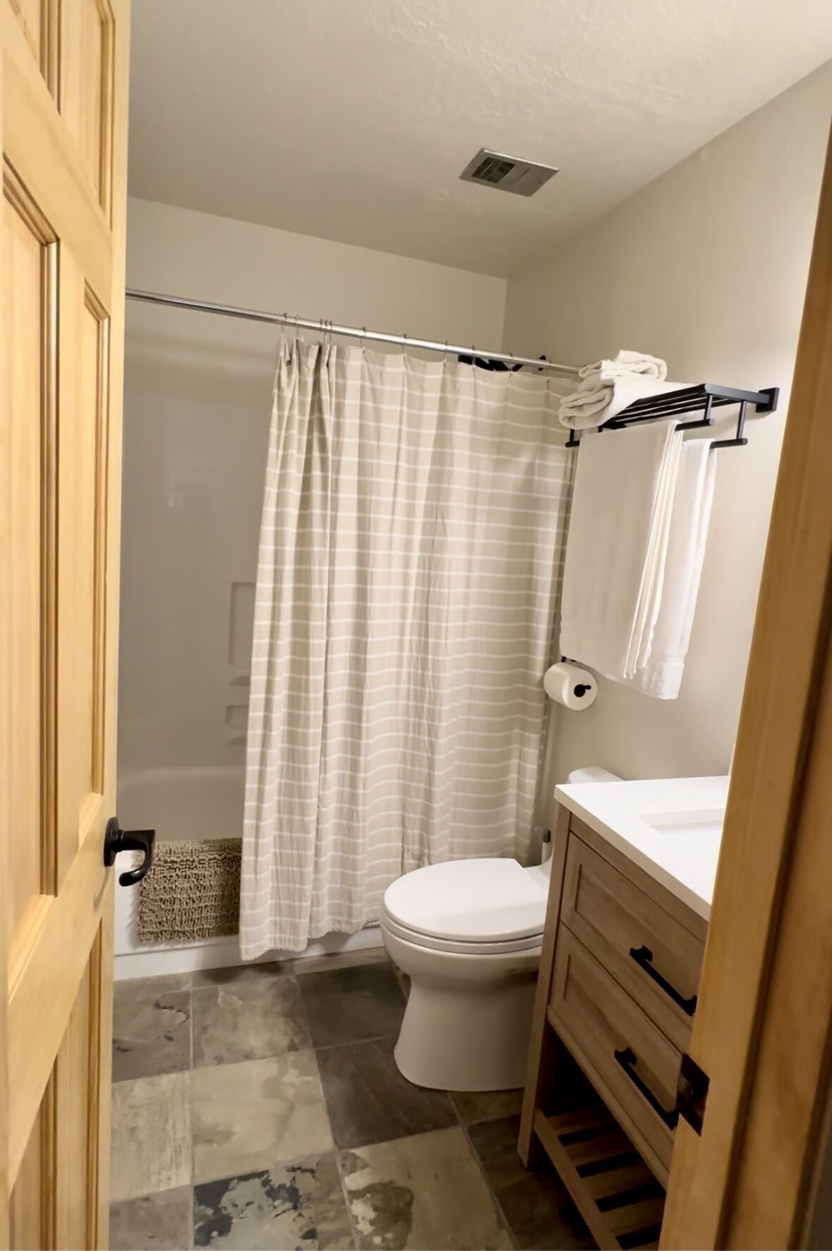 Ein Badezimmer mit Toilette, Duschvorhang, Handtuchhalter und Waschbecken.