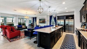 A modern kitchen with a central island, black cabinetry, stainless steel appliances, and blue accents. - Solara Sunshine (Kissimmee)