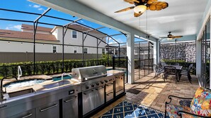 An outdoor patio with a grill, pool, and seating area. - Solara Sunshine (Kissimmee)